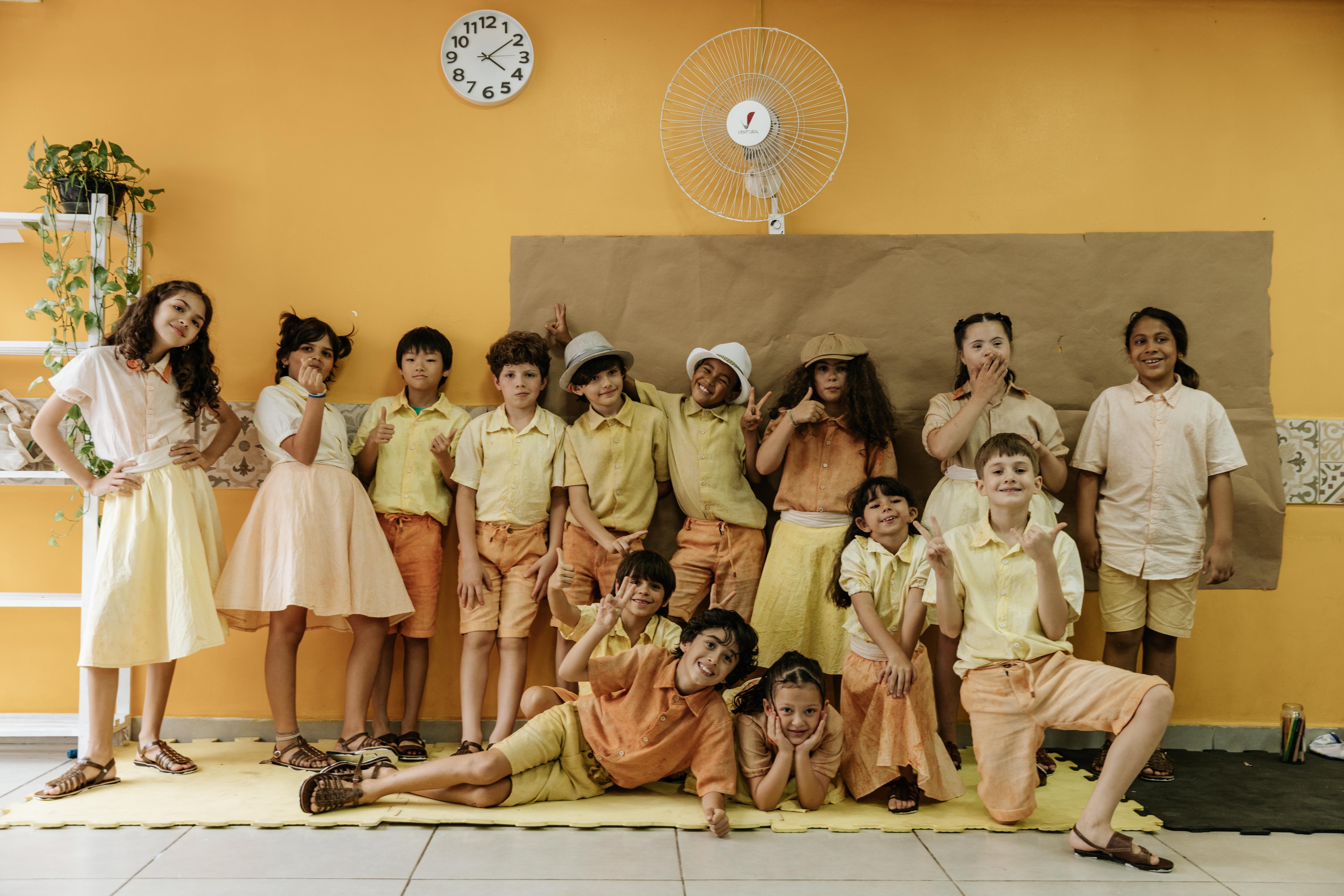 Turma do Ensino Fundamental I posando em grupo, vestidos com roupas temáticas em tons amarelos e laranjas